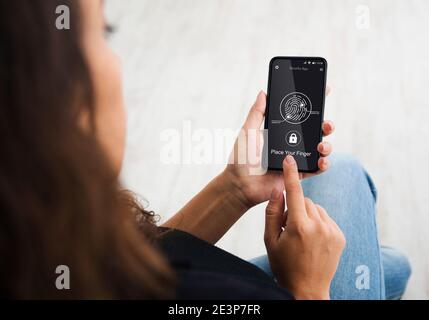 Unrecognizable Lady Unlocking Phone Scanning Fingerprint Sitting Indoors, Cropped Stock Photo