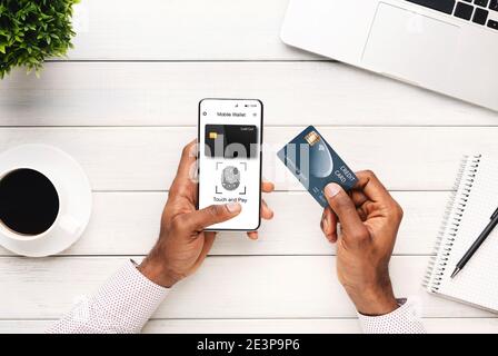 Black Man With Phone Using Mobile Wallet Application At Workplace Stock Photo