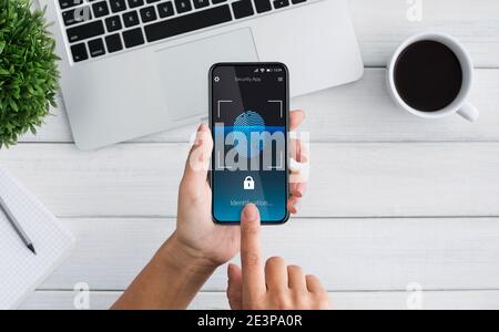 Woman Unlocking Smartphone Scanning Fingerprint For Biometric Identification Indoor, Top-View Stock Photo