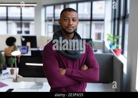 Portrait of mixed race businessman in creative office smiling with arms crossed Stock Photo