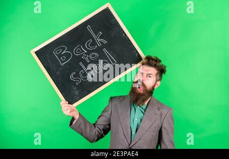 Teacher bearded man holds blackboard with inscription back to school green background. Keep working. Teacher with tousled hair stressful about school year beginning. Teaching stressful occupation. Stock Photo