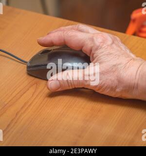 A woman uses a computer mouse. Female hand on a black computer mouse Stock Photo