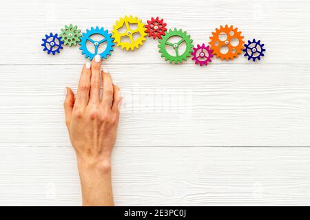 Teamwork concept. Hand connecting gears into puzzle - symbol of working mechanism Stock Photo