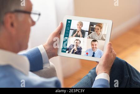 Senior Businessman With Tablet Having Online Meeting At Home, Cropped Stock Photo