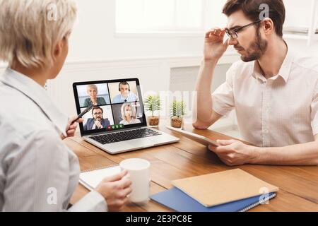 Businessman And Businesswoman At Laptop Communicating With Coworkers Online Indoors Stock Photo