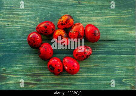 Macro photo of red easter quail egg. Painted red quail eggs on a green wood background. Easter Stock Photo