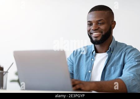 Handsome Black Male Office Employee Working On Laptop Computer, Closeup Shot Stock Photo