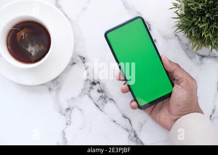 hand holding smart phone with empty screen on tile backgorund  Stock Photo