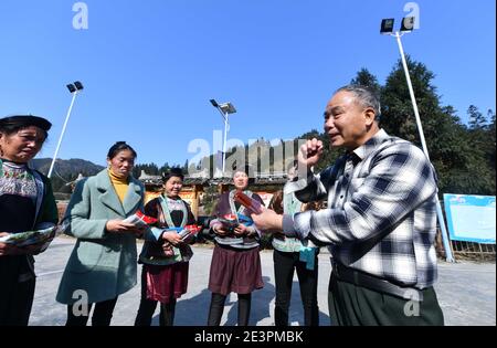 (210120) -- RONGSHUI, Jan. 20, 2021 (Xinhua) -- Lan Shengkui (1st R) introduces noodles made with red sorghum flour to villagers at Wuying Village, which lies on the border between south China's Guangxi Zhuang Autonomous Region and southwest China's Guizhou Province, Jan. 19, 2021. Wuying Village suffers from harsh environment and low agricultural yields, making it one of the most impoverished counties in Guangxi. In the summer of 2020, Lan Shengkui, a retired agricultural expert in variety improvement from Liuzhou Agricultural Science Institute, has come up with red sorghum, a crop that has Stock Photo