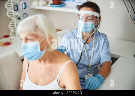 Medical person moving a stethoscope chest-piece on female back Stock Photo