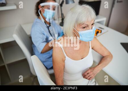 Pensioner having her back listened to with a stethoscope Stock Photo