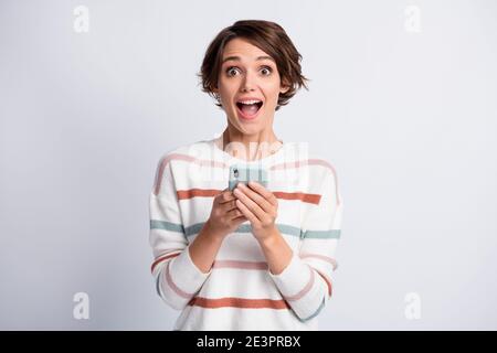 Photo of sweet impressed young woman dressed striped pullover holding modern device isolated grey color background Stock Photo