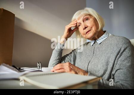 Sad aged woman sitting at the desk Stock Photo
