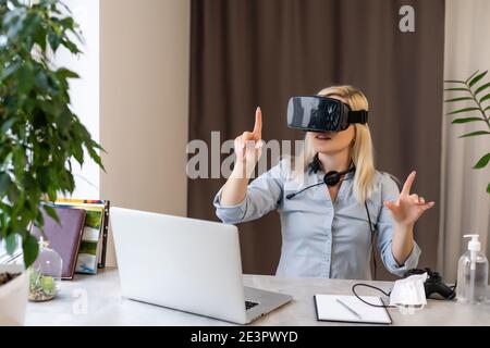 Female engineer working on computer creating a racecar using VR virtual reality glasses and controller. Concept for women in hightech jobs. Stock Photo