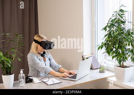 Female engineer working on computer creating a racecar using VR virtual reality glasses and controller. Concept for women in hightech jobs. Stock Photo