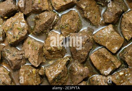 Diced sirloin beef chunks in marinade with herbs and spices. closeup full frame image. Stock Photo