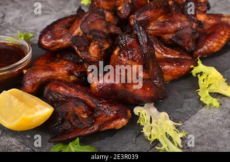 Grilled chicken wings on a plate with lemon and sauce. Roasted in oven crispy sticky honey chicken wings Stock Photo