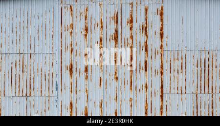 White and rusty wall of industrial hangar made of corrugated sheet steel -abstract background Stock Photo