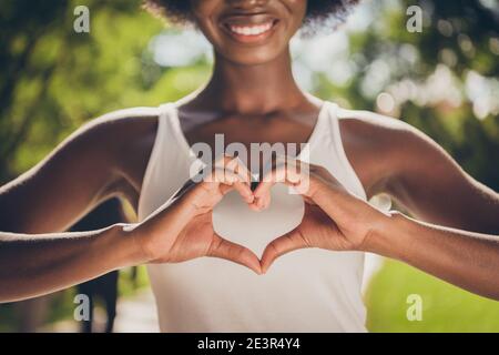 Close-up concept photo portrait of woman making heart with hands in park Stock Photo