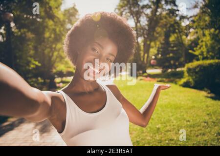 Photo portrait of shiny woman shooting selfie showing nature with hand in sunshine outdoors Stock Photo