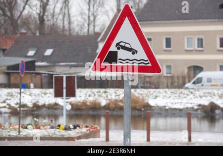 Anklam, Germany. 19th Jan, 2021. Flowers and candles stand at the scene of an accident in Anklam on the river Peene. A nine-year-old boy and a 43-year-old man died in a tragic slippery road accident. They had slid with their car on 13.01.2021 and fallen into a river. The fire brigade, which was alerted immediately, was unable to locate the sunken car in the five-metre-deep river Peene and thus could not help the car occupants. The driver was the partner of the mother of the boy who died. Credit: Stefan Sauer/dpa-Zentralbild/ZB/dpa/Alamy Live News Stock Photo