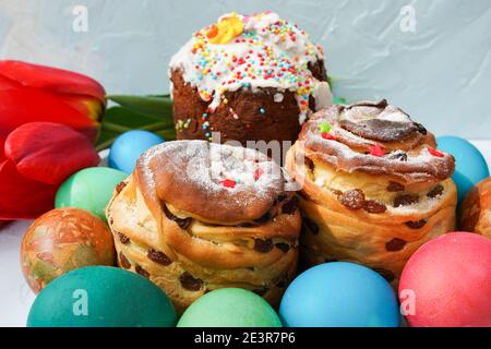 Russian Easter kulich paska decorated with painted colorful Easter eggs on dinner table with spring flowers Stock Photo