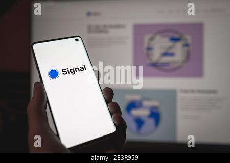 Man holding a smartphone with Signal wessenger sign and logo displayed on the screen in front of the Signal web version Stock Photo