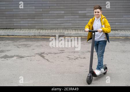 Modern teenager with backpack rides on electric scooter Stock Photo