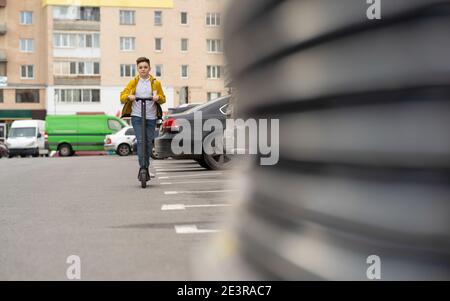 Teenager rides on electric scooter down street Stock Photo