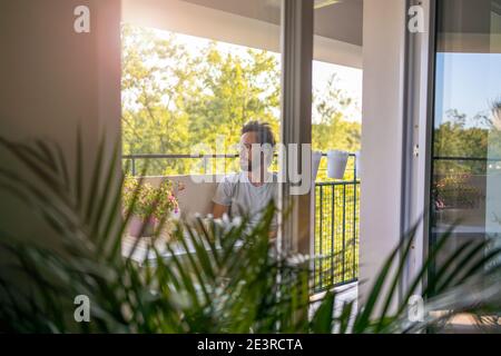 Man drinking coffee on the balcony of his apartment Stock Photo