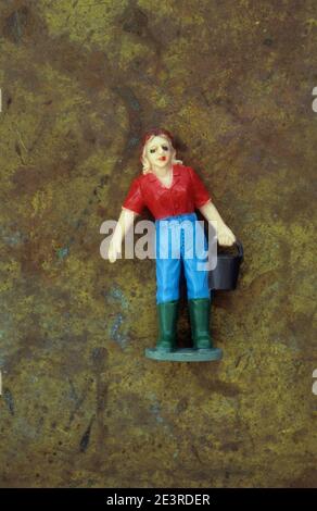 Plastic model of female farm or stable worker in jeans and rubber boots carrying bucket Stock Photo
