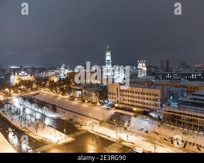 Winter snowy evening lights illuminated city aerial landscape. Dormition Cathedral, Serhiivskyi Maidan in Kharkiv downtown, Ukraine Stock Photo