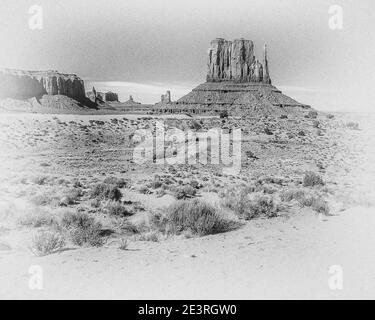 United States. The fabulous mountain and desert scenery of Monument Valley in monochrome in the Monument Valley National Park of Arizona in the United States. Seen here from near John Ford Point overlook that was used during the epic filming of the attack and hair raising chase by so called hostile Red Indians of the six team horse driven Wells Fargo Stage Coach in the Western film Stagecoach that starred a very young up-coming actor called John Wayne, its a classic piece of movie making. Stock Photo