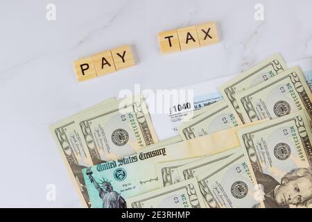 Text write PAY TAX American Internal Revenue Service individual income tax form 1040 at stimulus economic tax return check of USA many currency Stock Photo
