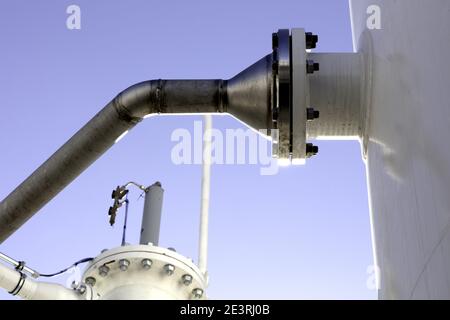 pressure joint with screws of a steel pipe to a white tank Stock Photo