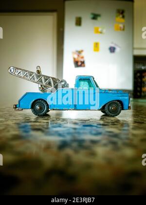 A child's toy tow truck on a kitchen worktop, with a fridge in the background Stock Photo