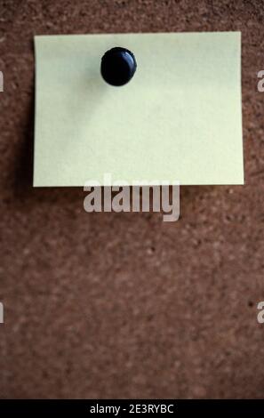 Blank yellow sticky note pinned to a noticeboard Stock Photo