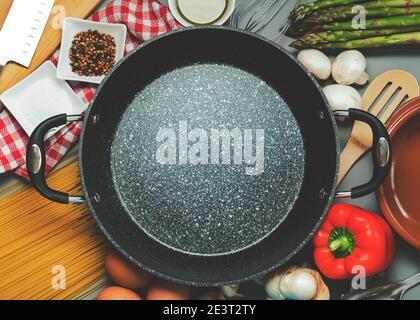 Top view of empty frying pan with ingredients for cooking on grey background