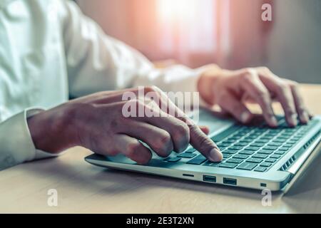 Businessman hand typing on computer keyboard of a laptop computer in office. Business and finance concept. Stock Photo