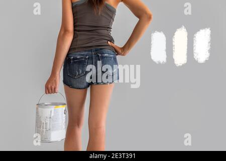 Home renovation woman confused between different shades of white paint choosing tones of warm and cold whites in eggshell sheen. Girl painting walls Stock Photo