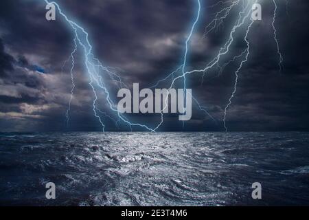 Lightning strike over the ocean. Bolt of lightning over stormy dark sea during a thunder-storm with dramatic cloudscape. Stock Photo