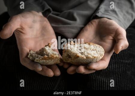 Hunger concept. Pieces of bread in the hands of a man. Poverty. Stock Photo