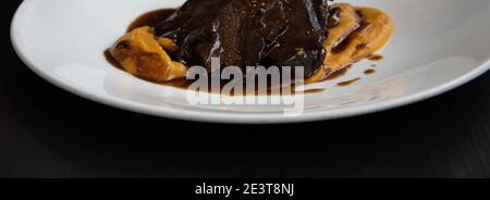 Juicy stewed beef in red wine sauce served with sweet potato puree. Gourmet comfort food background banner. Stock Photo