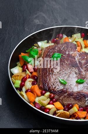 Braised  beef with cranberries and vegetables on black stone background Stock Photo