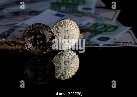 Two cryptocurrency coins on a black background and paper money. The image has a reflection on the surface and space for the text. Stock Photo
