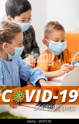 multicultural children in medical masks using gadgets while programming robot in stem school, covid-19 illustration Stock Photo
