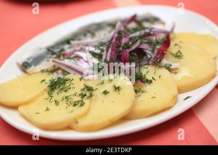 Potatoes with onions and herring on a plate Stock Photo