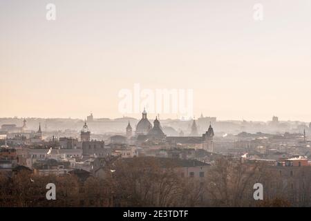 Atmospheric view down onto the misty outlines of domes, churches, landmark buildings and rooftops of central Rome, Italy, from Trastevere, at sunrise Stock Photo