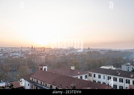 Atmospheric view at sunrise over rooftops of Trastevere down onto the misty outlines of central Rome, Italy, across the River Tiber. Stock Photo