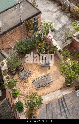 Aerial view looking down onto a roof garden terrace in Trastevere, Rome, Italy.  A table and chairs on a small patio, and plants in containers. Stock Photo